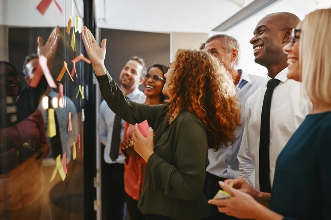 Coworkers working on a board with sticky notes