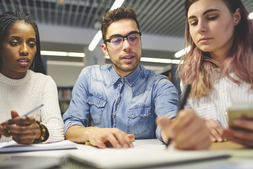 Three coworkers write notes down while brainstorming