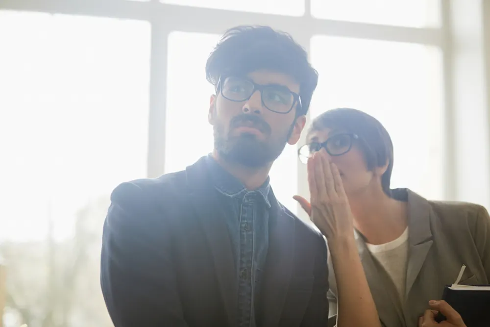 Woman whispers to coworker