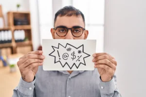 man holds card with signs indicating foul language