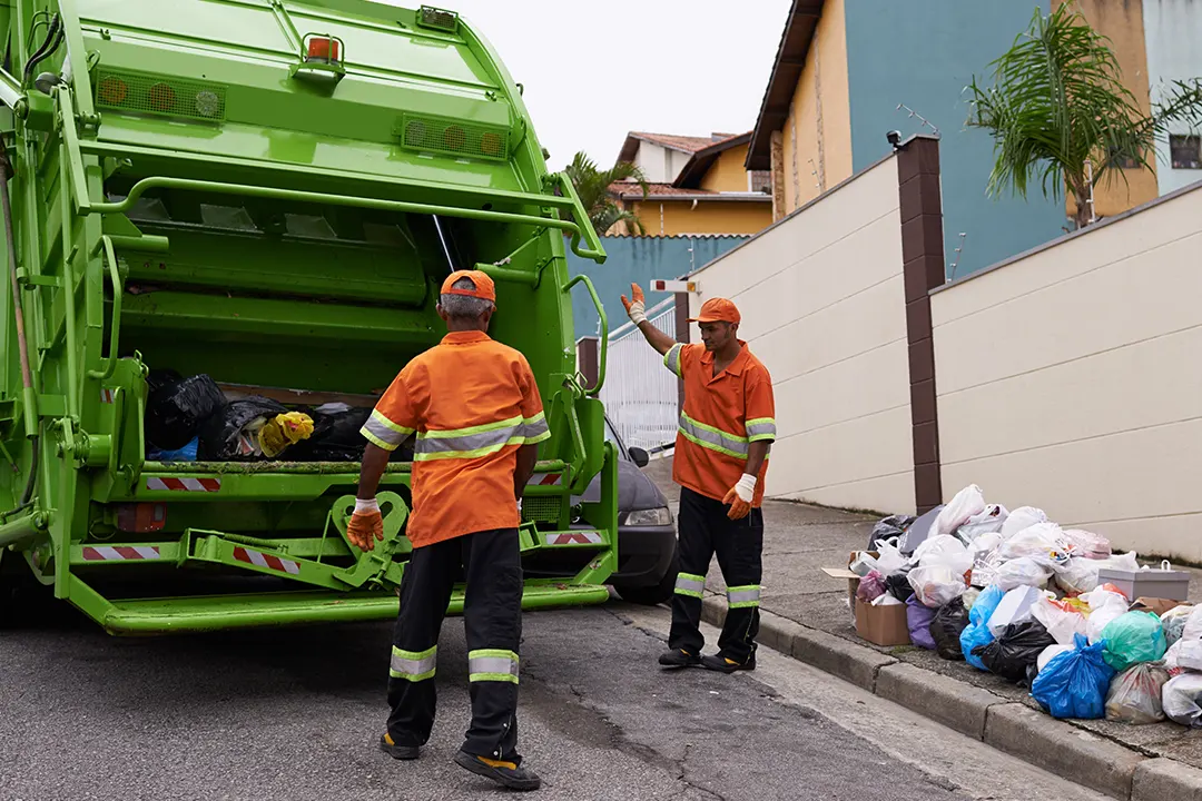 Sanitation workers toss trash into truck