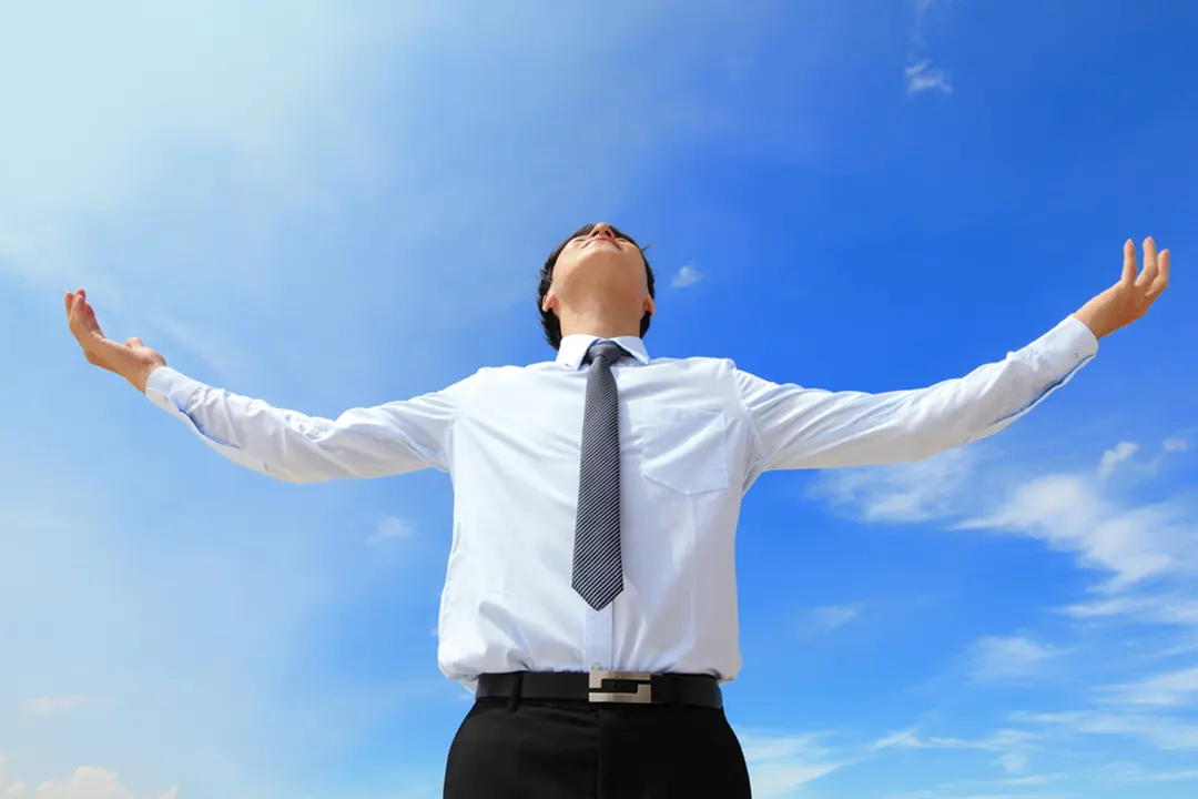 Man holds out arms and look up at sky