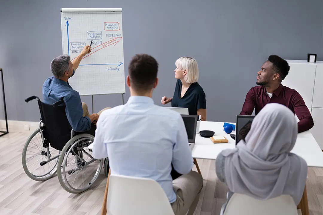 Workers meet to review charts on a paper flipboard