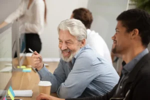 Colleagues talk in front of a laptop
