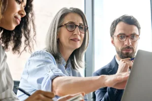 Three coworkers look at laptop