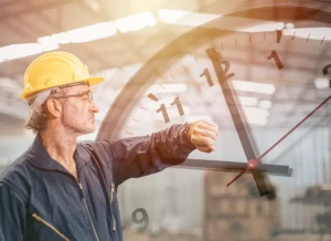 A construction worker in a hard hat looks at his watch with a clock superimposed in the background
