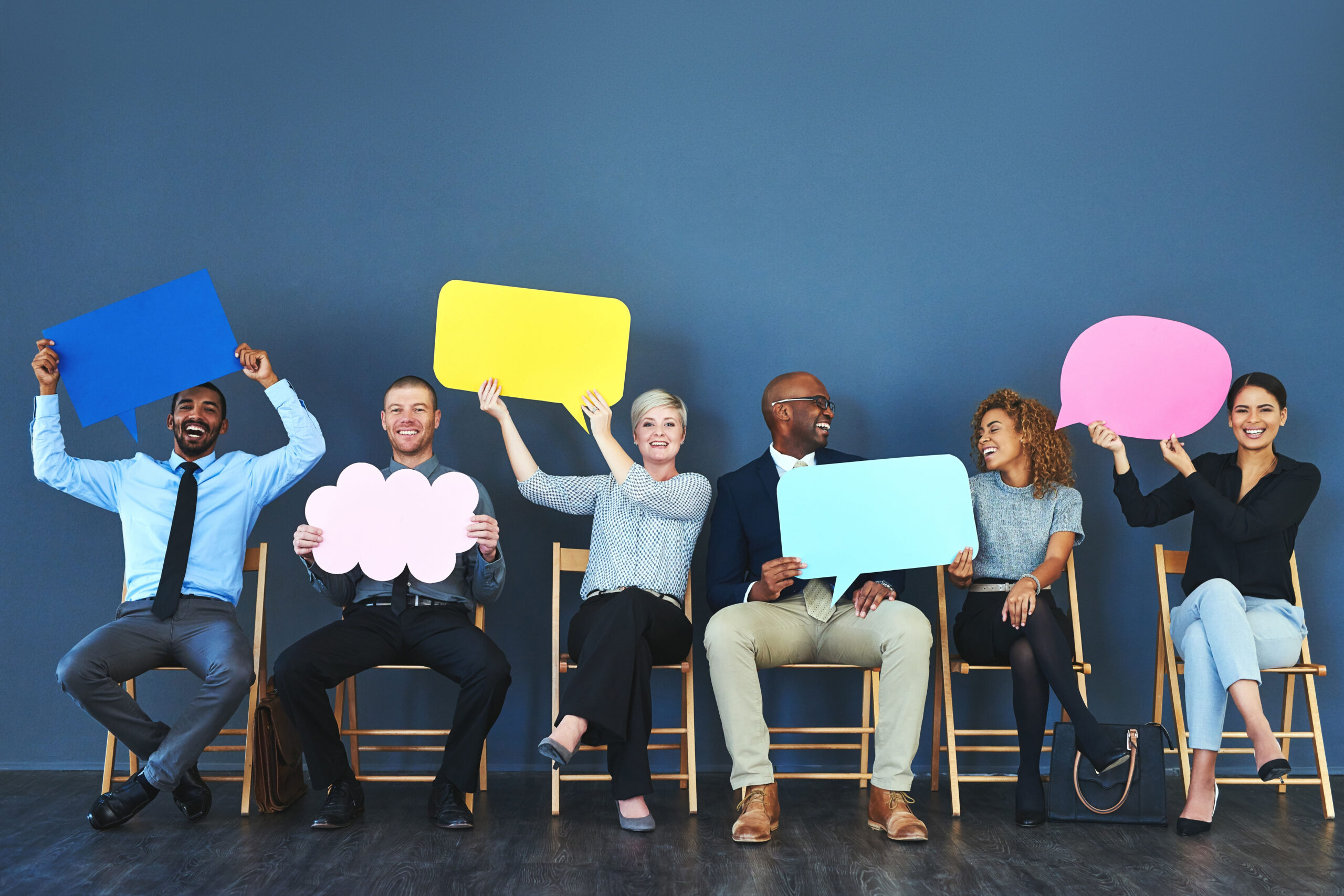 A diverse group of employees or candidates hold up speech bubbles of different colors