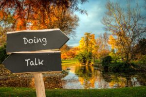 A sign that says "Doing" pointing one way and a sign that says "Talk" pointing the other way