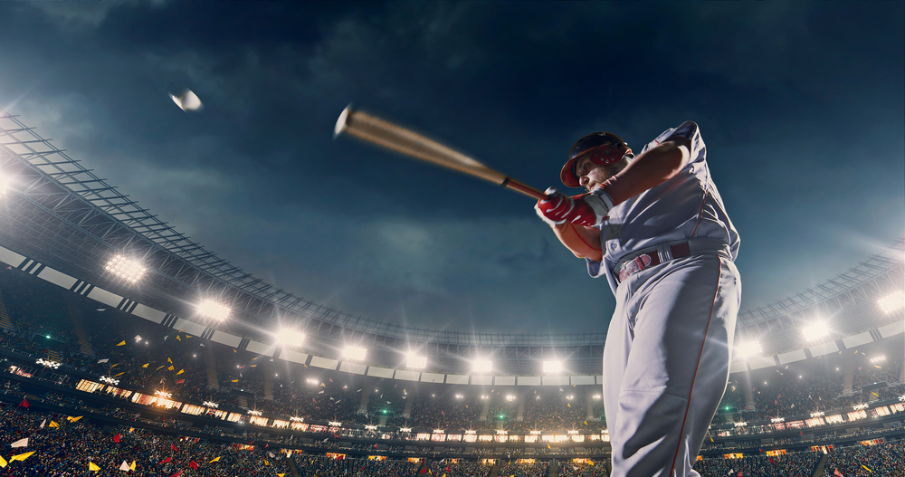 A baseball player swings a bat and hits the ball hard