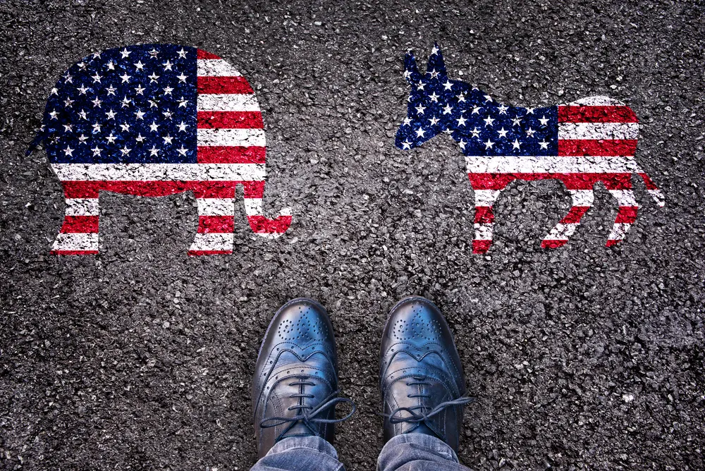 Man stands near Republican and Democrat party symbols painted on ground