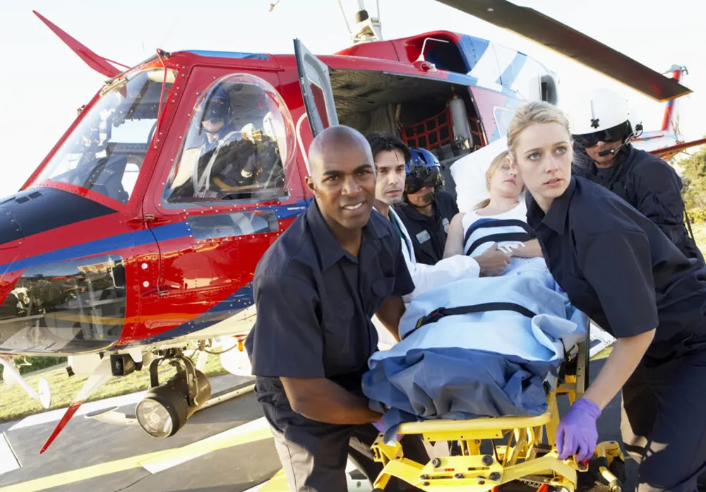A team of EMTs escorts a patient on a stretcher from a helicopter to an ER.