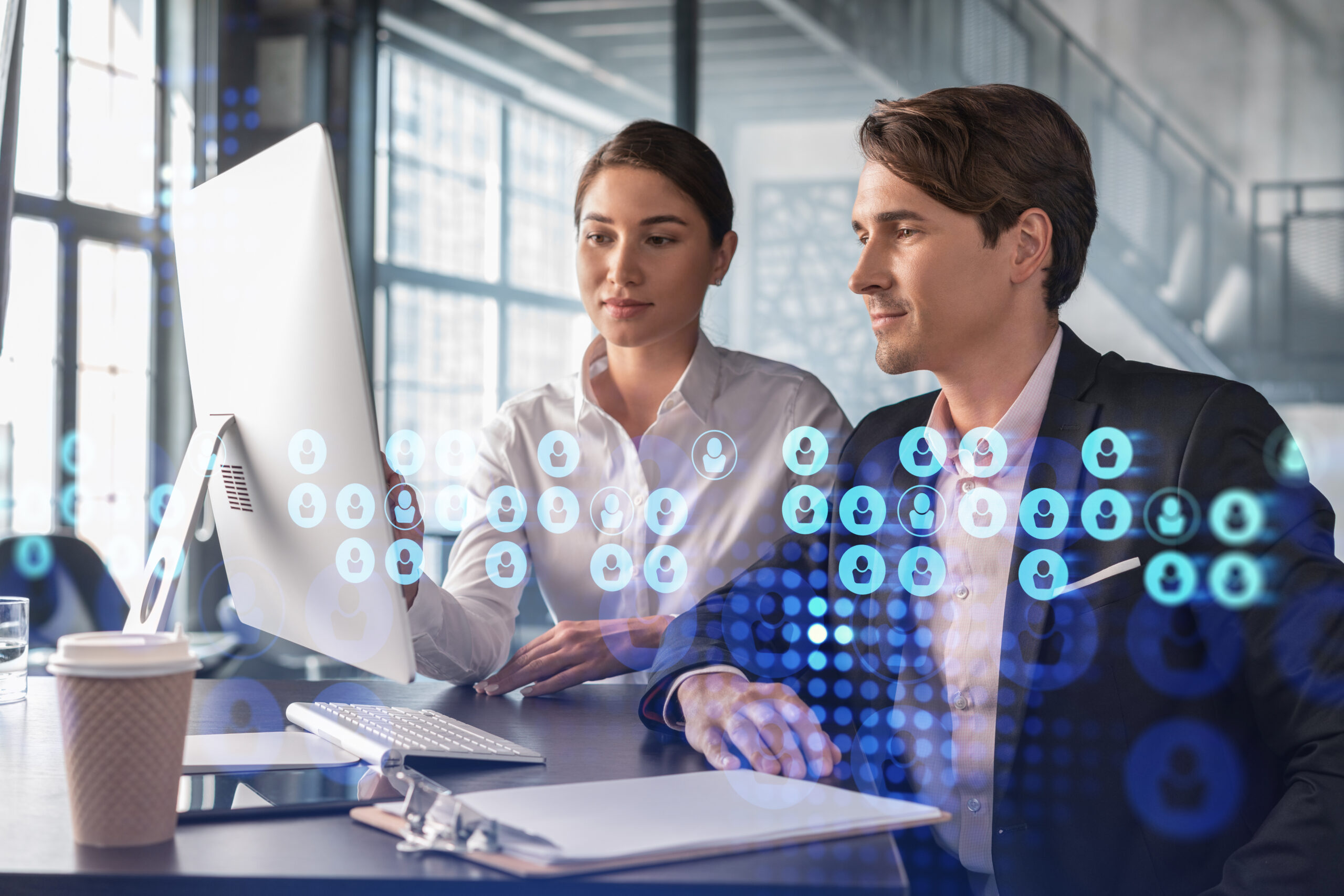 A woman and a man sit side by side in front of a computer, using people analytics to evaluate candidates for a job opening