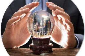A man in a business suit and tie holds his hands over a crystal ball, in which he sees skyscrapers.