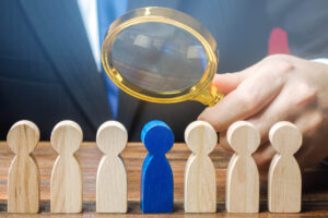 Businessman holds a magnifying glass over a worker. Recruitment concept. Hiring, hire. The best employee, leader. Leadership and promotion. Human Resource Management. Toxicity in the team.
