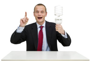 A businessman, smartly dressed in a suit, holding a lamp, illustrating the idea and innovation process. On the whiteboard behind him, a schematic innovation funnel is drawn;