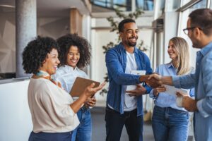 Diverse group of professionals smiling and shaking hands modern office environment teamwork collaboration positive business relationships