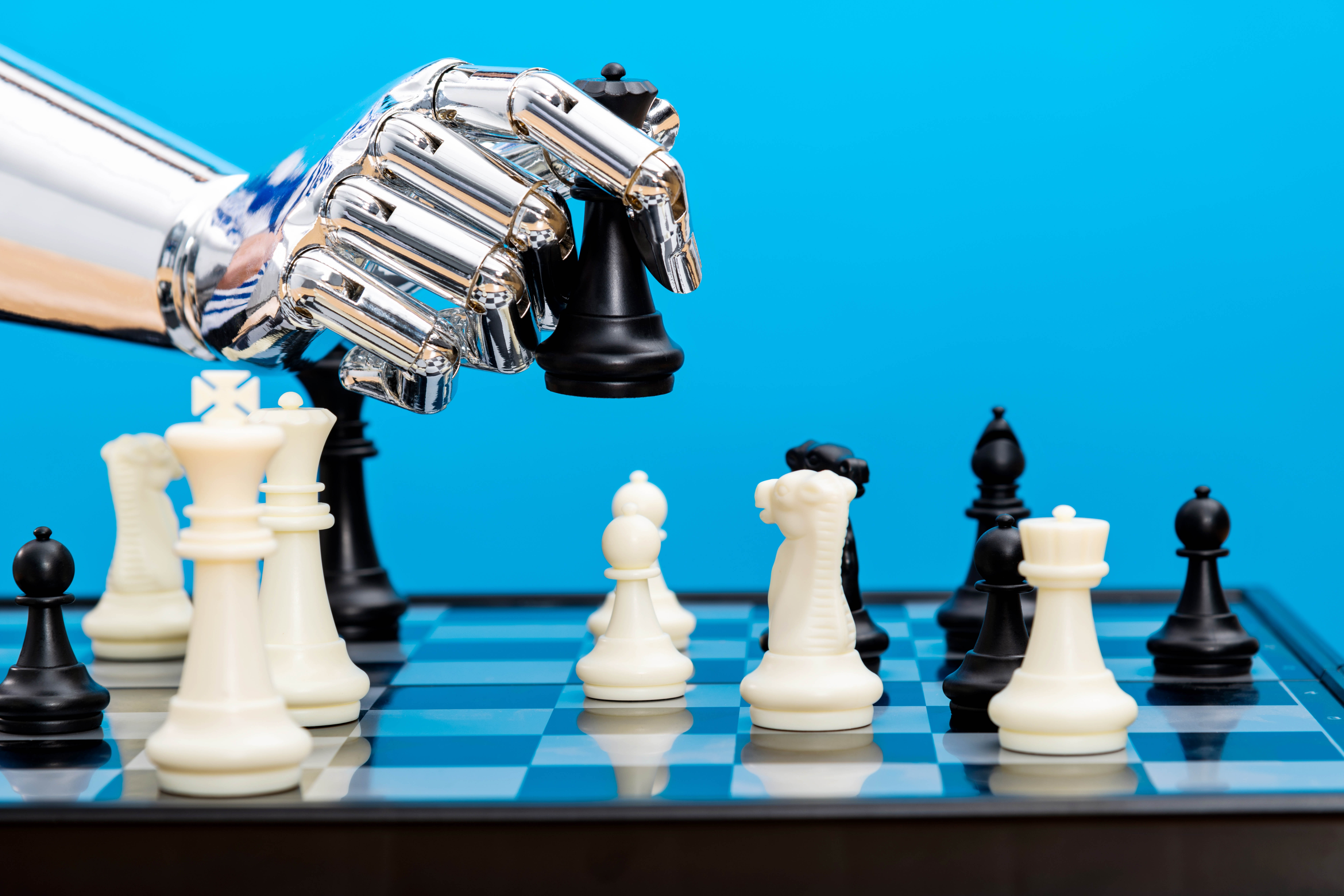 Robot hand holding chess pieces.