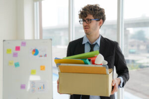 unemployed young man holds the document box, Layoffs occur when a company undergoes restructuring or downsizing or goes out of business. Unemployment in the Corona Virus Crisis (COVID-19)