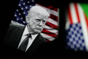 In this photo illustration, US President Donald Trump is seen behind United States of America flag, with all of them displayed on screens, in Turin, Italy on February 23, 2026.