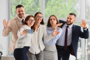 Corporate culture and team building, diverse business colleagues taking a selfie together in a modern office to celebrate success and collaboration