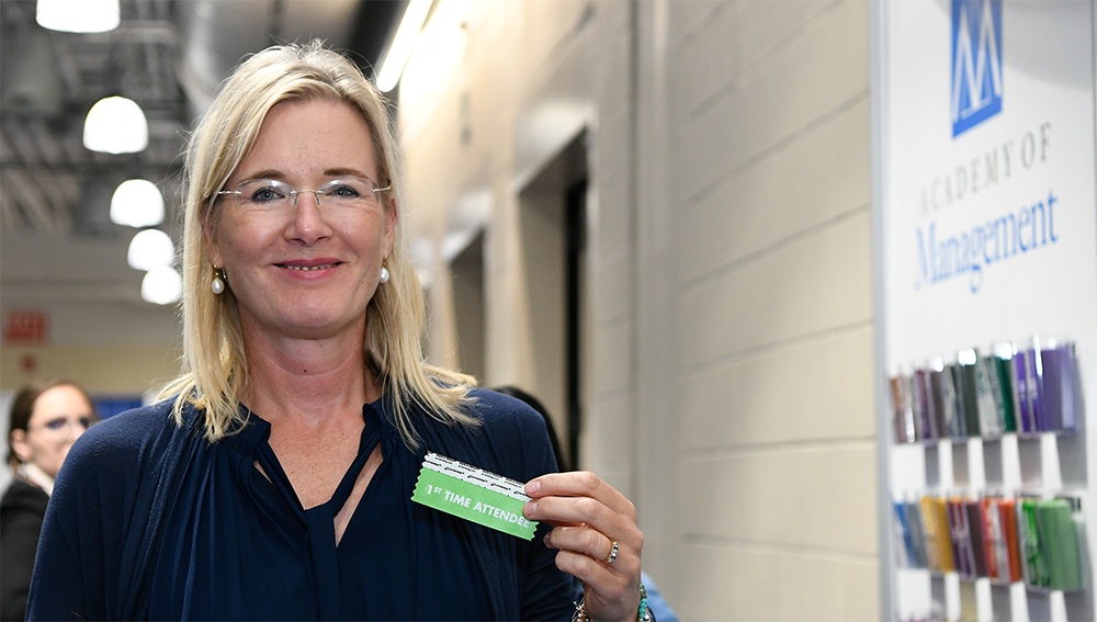 Image of member holding up First Time Attendee ribbon